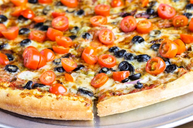 Veggie пицца с оливками и помидорами черри на столе.