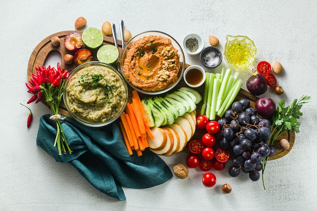 Veggie serveertafel met snacks met groenten fruit baba ganoush en dip of verspreiding van geroosterde rode peper en noten gezond veganistisch eten voor feest of vrienden geschoten van bovenaf kopieerruimte