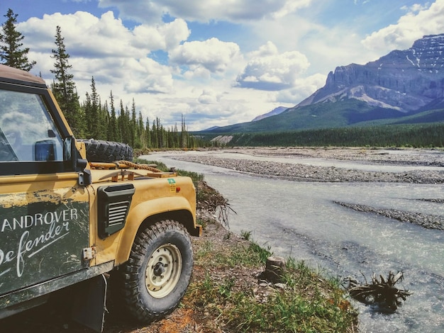 Vehicle by river against sky