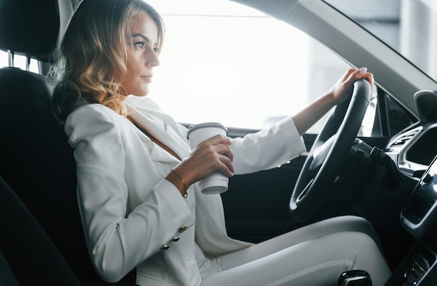 Vehicle interior Woman in formal clothes is indoors in the autosalon