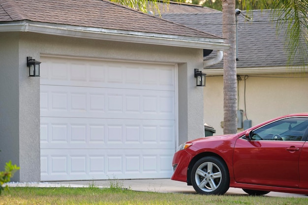 典型的な現代的なアメリカの家の舗装された私道の広いガレージの両開きドアの前に駐車した車両