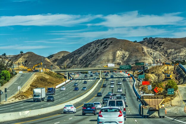 Vehicles on road by mountain against sky