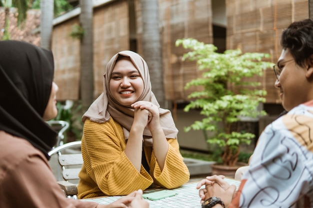 ベールに包まれたアジアの女の子はチャットしながら幸せそうに笑う