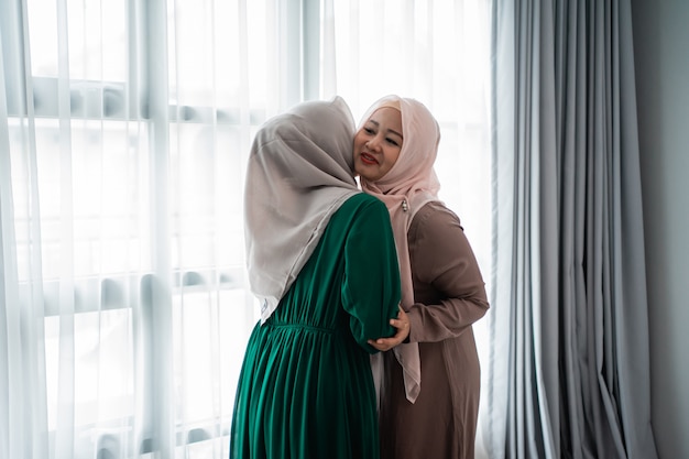 Veiled woman hugs and kiss her sister when meeting