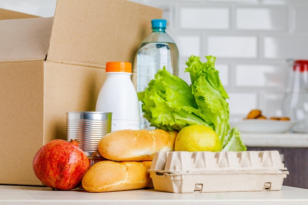 Veilig thuisbezorgd Een doos met diverse producten zoals melkfruit en brood in de keuken