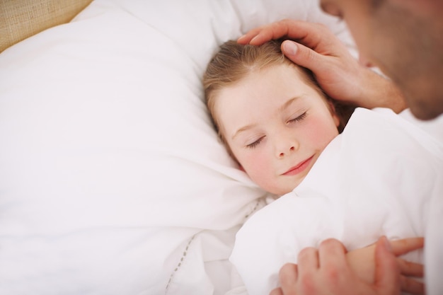 Veilig weggestopt Een vader die zijn dochter liefdevol naar bed brengt