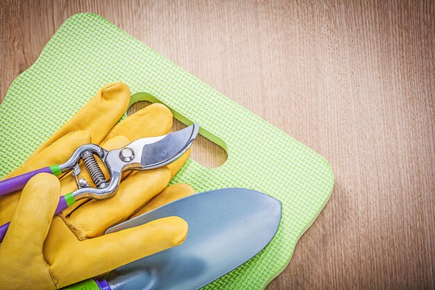 Veiligheidshandschoenen knielende pad hand troffel tuinsnoeischaar op houten plank tuinieren concept