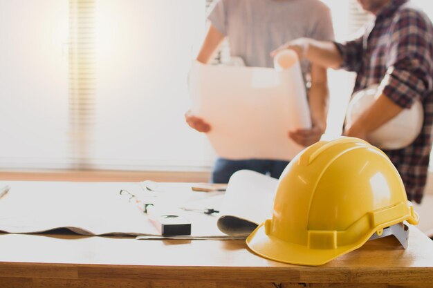 veiligheidshelm op tafel met ingenieur met blauwdruk achtergrond