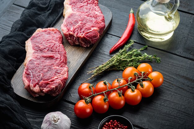 Bistecca venosa, carne cruda di manzo marmorizzata, sul tavolo di legno nero