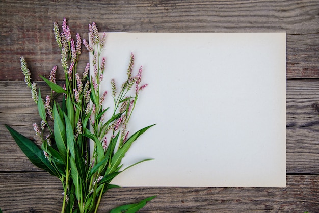 Vel papier en de kleine roze bloemen op hout