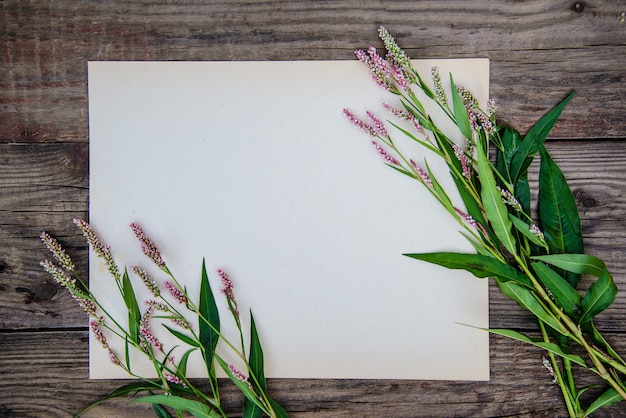 Vel papier en de kleine roze bloemen op houten tafel