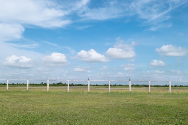 Veld met groen gras en metalen hek