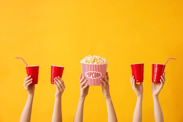 Vele handen met popcorn en kopjes drank op kleur