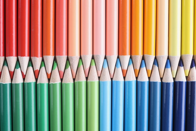 Vele tinten scherpe veelkleurige houten potloden die in kleuren van de achtergrond van de regenboogclose-up liggen