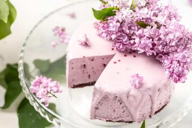 Velvet mousse cake with blueberries decorated with a bouquet of purple blooming lilac French cuisine postcard background