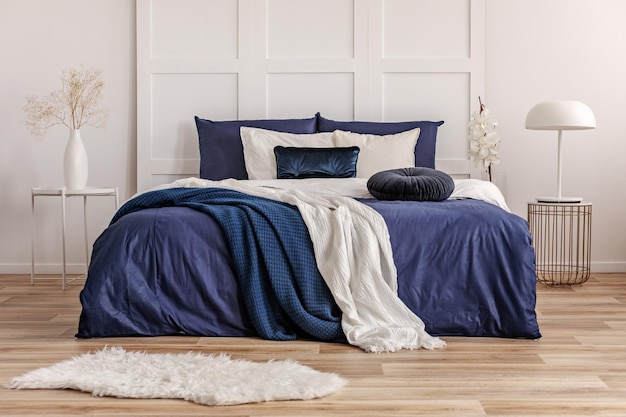 Velvet round pillow on king size bed with blue and white sheets