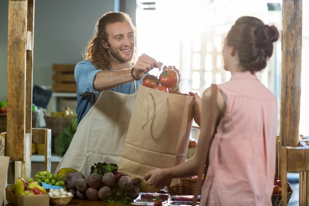 Foto venditore che consegna un sacchetto di verdure alla donna al negozio di alimentari