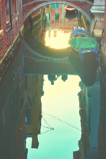 Venetiaanse spiegel - Huizen, zonsonderganghemel en kleine brug weerspiegelen in kanalenwater, Venetië