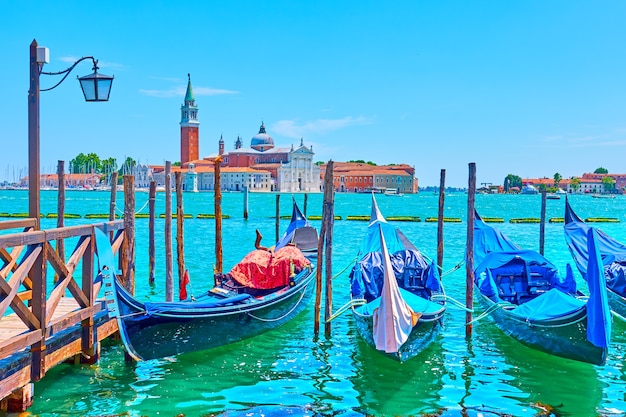 Photo venetian cityscape with moored gondolas and san giorgio di maggiore church in venice, italy on sunny summer day