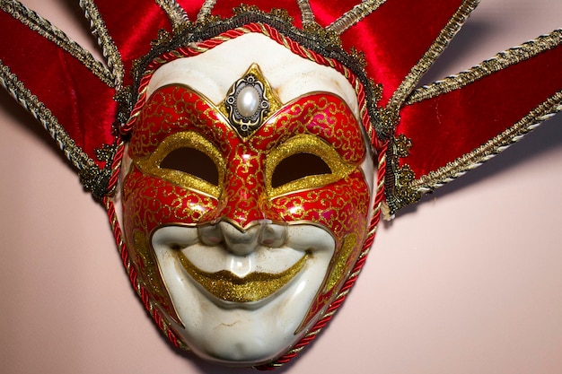 Venetian jester mask on a pink background top view