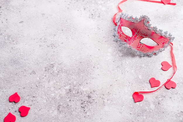 Venetian mask and valentines hearts on stone background. Blind date concept, copy space