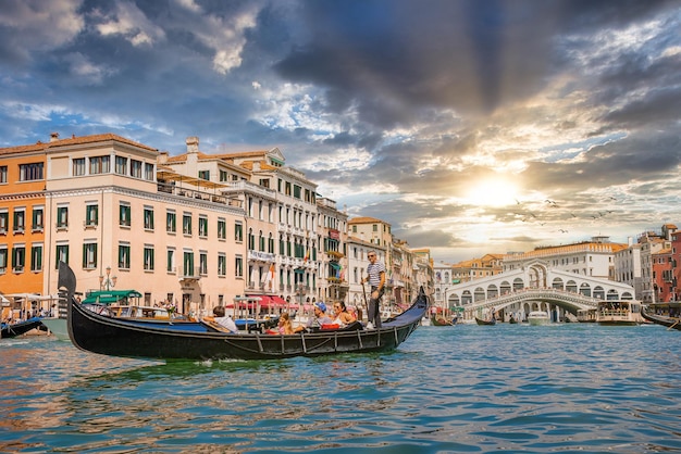 Venetië, Italië. 10 augustus 2021. Venetiaanse gondelier punteren gondel door de grote kanaalwateren van Venetië, Italië in de buurt van de Rialtobrug.