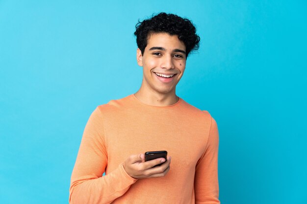 Venezolaanse man geïsoleerd op blauw met behulp van mobiele telefoon