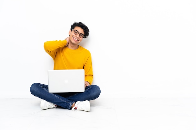 Venezolaanse man zittend op de vloer met laptop lachen