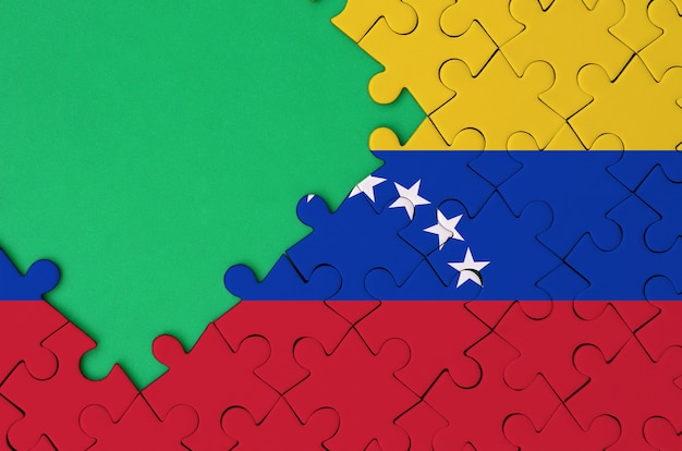 Venezuela flag  is depicted on a completed jigsaw puzzle with free green copy space on the left side