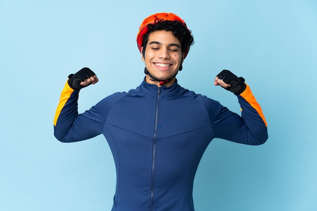 Venezuelan cyclist man on blue doing strong gesture