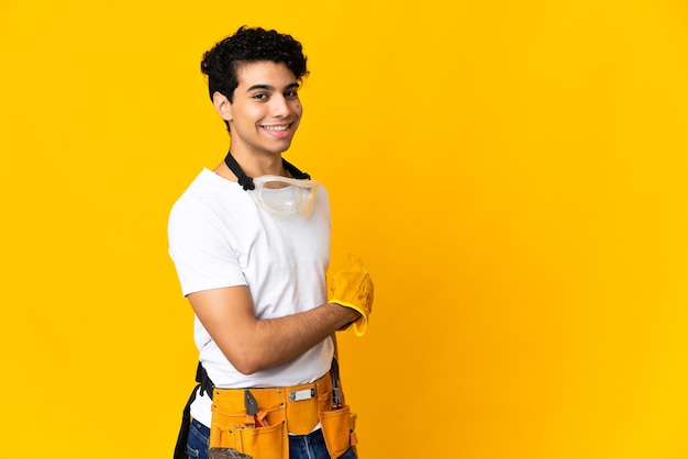 Venezuelan electrician man isolated on yellow  pointing back