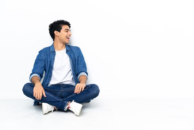 Venezuelan man sitting on the floor laughing in lateral position