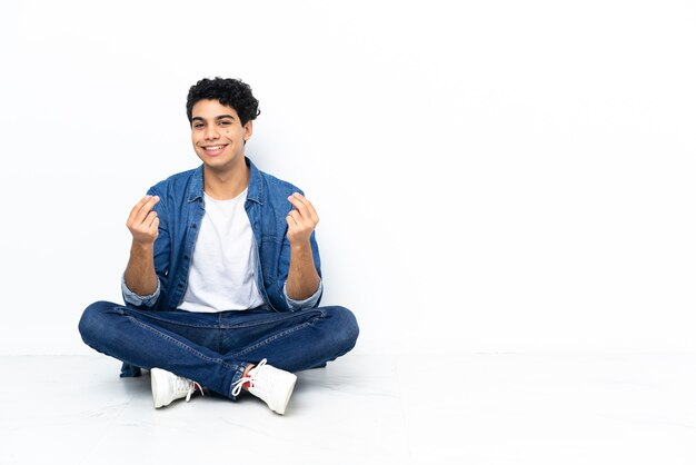 Venezuelan man sitting on the floor making money gesture