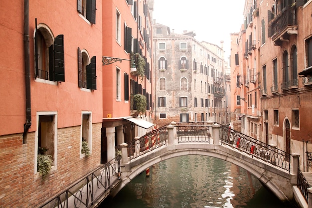 Venice bridge. small bridge between houses on venice canal on\
winter misty day in venice, italy