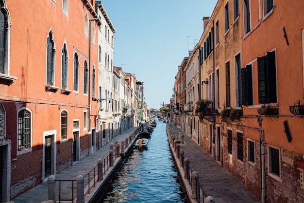 Venice, Italië - 1 juli 2018: Panoramisch uitzicht over het smalle kanaal van Venetië met historische gebouwen en boten vanaf de brug. Landschap van zonnige zomerdag