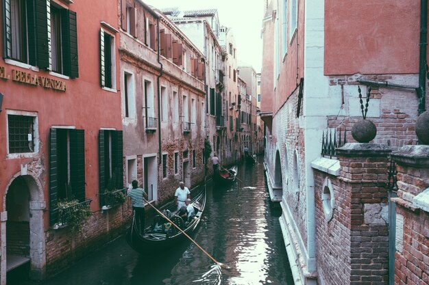 Venice, Italië - 2 juli 2018: Panoramisch uitzicht over het smalle kanaal van Venetië met historische gebouwen en gondels vanaf de brug. Zanger zingt in een gondel. Zomer zonnige dag en zonsondergang hemel