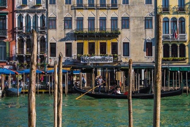 Venice italy august 28 2021 view of the gondola taking tourists along the grand canal of venice with typical houses in the background