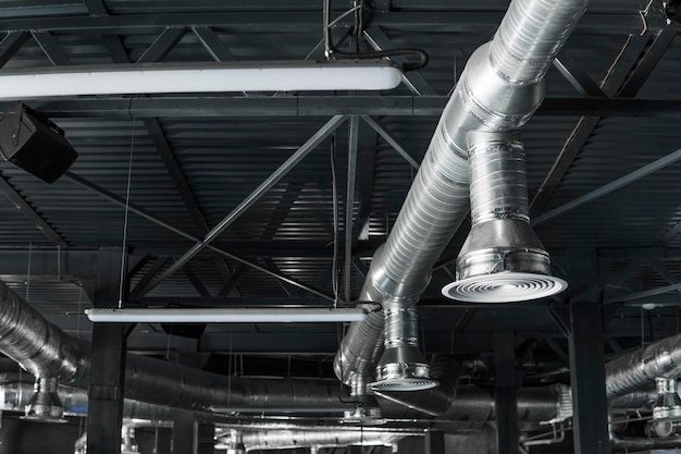 Photo ventilation pipes in silver insulation material hanging from the ceiling inside new building