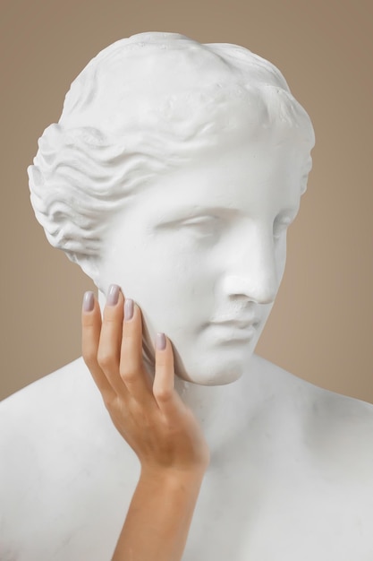 Photo venus sculpture with human womans hand on beige background