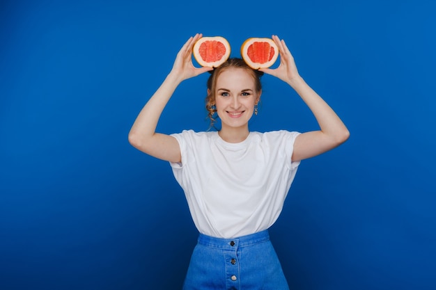 Verbaasd houdt het lachende meisje de grapefruit als oren vast