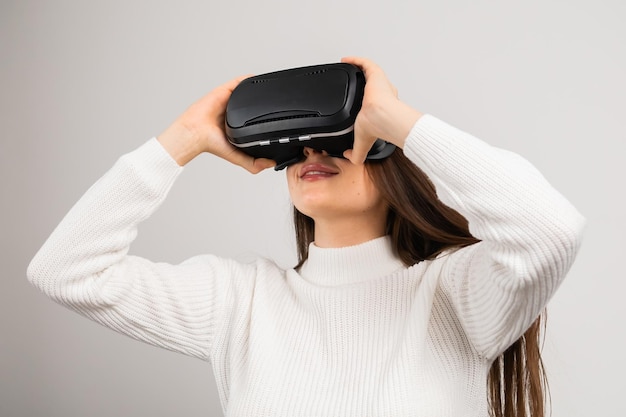 Verbaasd jong meisje in virtual reality met behulp van vr-bril headset verkent metaverse op de witte backgr