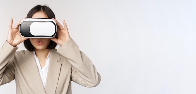 Verbaasd kantoor vrouw Aziatische zakenman in pak dragen vr headset kijken naar smth in virtual reality bril met onder de indruk wow gezicht witte achtergrond