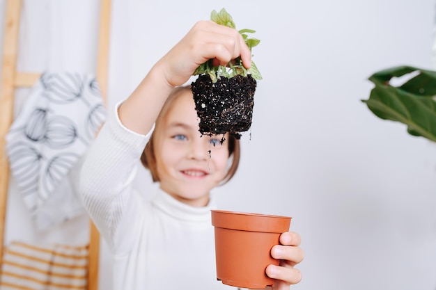 Verbaasd meisje met vuile plantenwortels nam de vorm aan van een pot