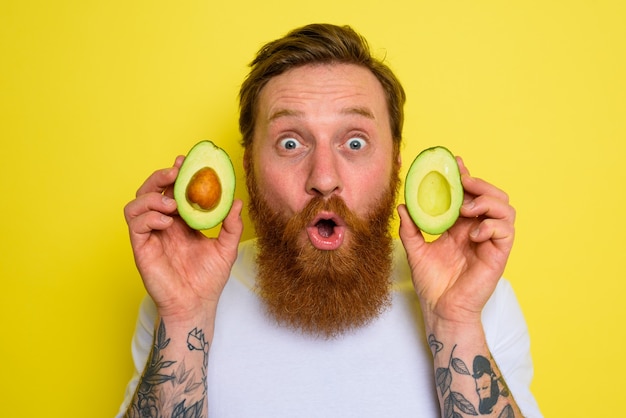 Verbaasd over baard en tatoeages houdt een avocado vast