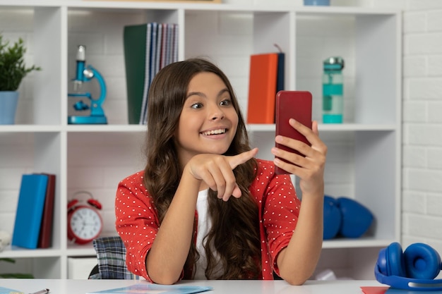 Verbaasd tienermeisje dat video maakt met een wijzende vinger op selfie met behulp van de maker van mobiele telefooninhoud