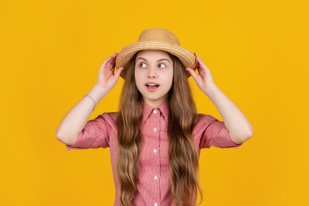 Verbaasd tienermeisje in strohoed op gele achtergrond