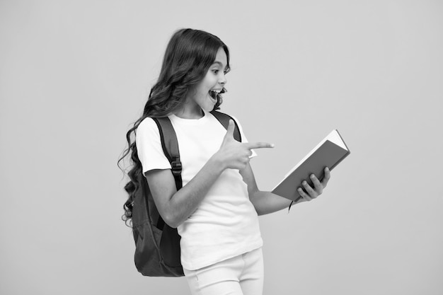 Verbaasd tienermeisje Schoolmeisje tiener kind met boek en voorbeeldenboek Tiener schoolmeisje student met