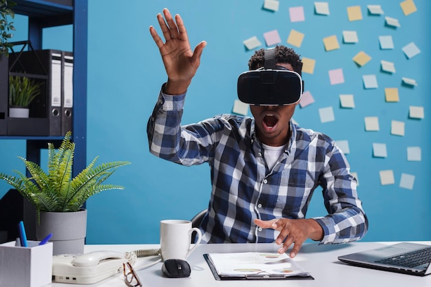 Verbaasde, bange kantoormedewerker die een virtual reality-headset draagt terwijl hij geniet van een simulatiespel. marketingbureau verbaasde verraste werknemer die met vr-technologie speelde terwijl hij in kantoorruimte was.