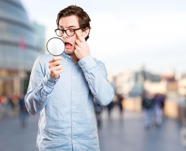 Verbaasde jonge man met behulp van een vergrootglas