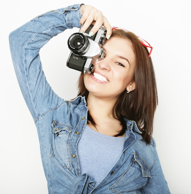 Verbaasde jonge mooie vrouw met camera op witte achtergrond.